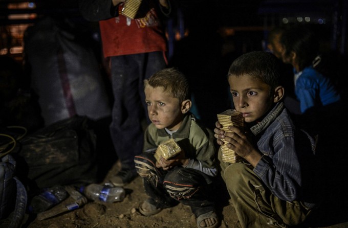 Syrian Kurdish children receive food after crossing the border near the southeastern town of Suruc in Sanliurfa province, on September 21, 2014. (Bülent Kılıç/AFP)