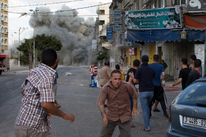 July 18, 2014. An Israeli bomb exploded in Gaza City. A small blast had warned residents to move away from the area, followed by the large one, which severely damaged its target. (Tyler Hicks/The New York Times)
