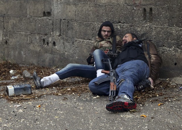 A Syrian rebel yells as he is hit by Army sniper fire as they prepared to attack a government controlled checkpoint in the Ain Tarma neighborhood of Damascus January 30, 2013. The rebel on the left would soon be hit by sniper fire. (January 30, 2013)