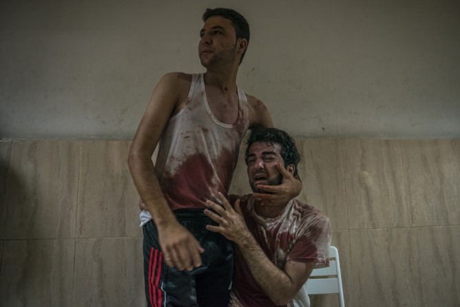 July 23, 2014. Brothers grieve for their father, killed in shelling in Khan Yunis, Gaza. (Sergey Ponomarev for The New York Times)