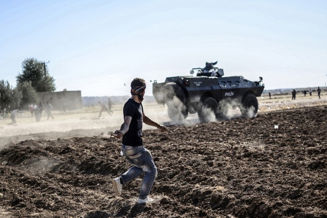 Kurdish protesters clash with Turkish soldiers near the Syrian border after Turkish authorities temporarily closed the border, preventing Syrian Kurds who accompanied their families to safety inside Turkey, from returning to the battlefront on September 22, 2014 at the southeastern town of Suruc in Sanliurfa province. (Bülent Kılıç/AFP)
