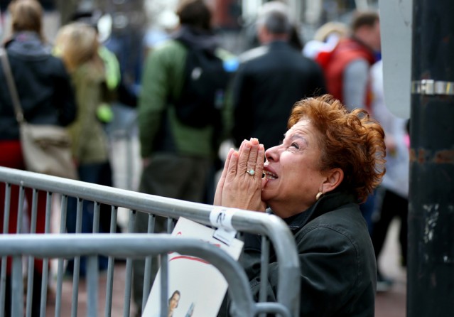 A woman kneels and prays near the scene of the first bombing on Boylston Street. Three people died and at least 260 were injured. (Photo by John Tlumacki, April 16, 2013)