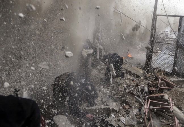 Debris flies through the air as Syrian rebel fighters take cover from a Army tank shell which hit a nearby wall during heavy fighting in the Ain Tarma neighborhood of Damascus (January 30, 2013)