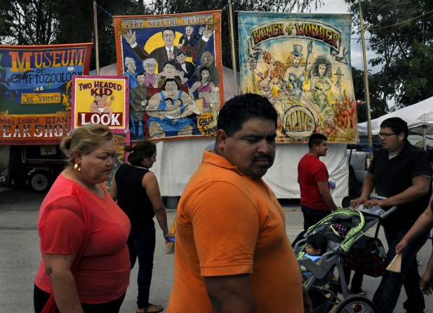 McAllen, Tex.: Residents pass an old-fashioned sideshow at the Alamo Flea Market. The obesity rate around Hidalgo County, one of the poorest and fastest-growing U.S. counties, is 38.5 percent. Children now living in this county are not expected to live as long as their parents.  (November 8, 2013)