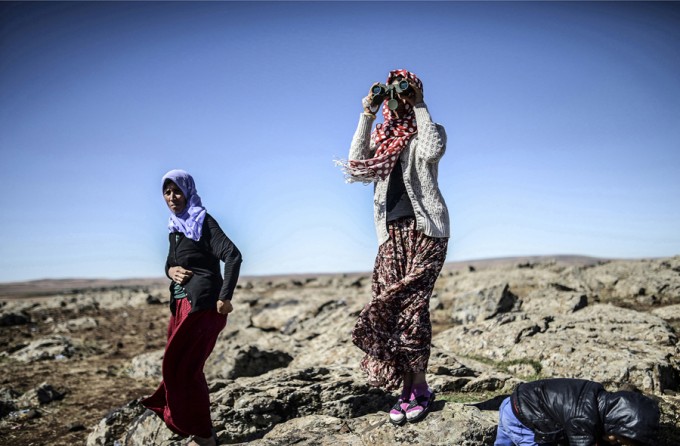 Members of the Syrian Kurdish Altay family try to spot on October 20, 2014 from the Turkish Syrian border village of Mursitpinar, their relative, Zamani Suruc, who is fighting Islamic State (IS) jihadists in the Syrian border town of Kobane. (Bülent Kılıç/AFP)