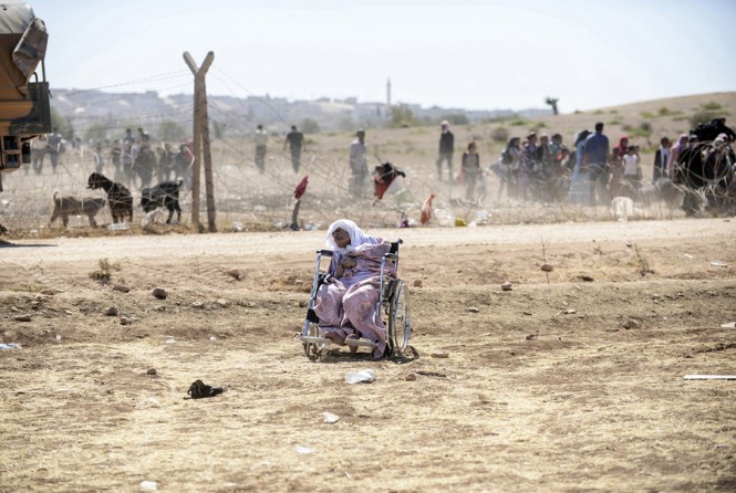An elderly Syrian Kurd sleeps in her wheelchair after she crossed the border between Syria and Turkey near the southeastern town of Suruc in Sanliurfa province, on September 20, 2014. Several thousand Syrian Kurds began crossing into Turkey on September 19 fleeing Islamic State fighters who advanced into their villages. (Bülent Kılıç/AFP)