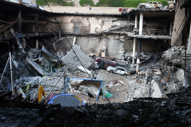 A section of the mall's parking lot crumbled, sending vehicles tumbling into an enormous, smoking pit. (Tyler Hicks, The New York Times - September 30, 2013)