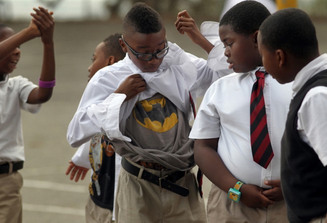 Ray Byrd, center, shows off his Batman t-shirt to Ciaran Johnson (l-r) and Alonzo Swift as they prepare to go back to their fourth-grade class after recess. The boys were putting their clothes back in place after playing hard during their break. (August 25, 2013)