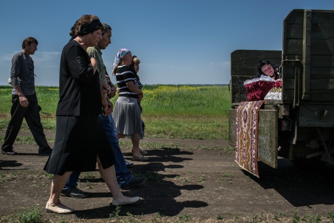 May 19 2014. Nadezhda Sanzharevskaya, 49, mourns her sister Yelena Ott, 42, following the truck carrying the coffin to the cemetery in the small village of Starovarvarovka, eastern Ukraine. The victim's husband said she was shot near a checkpoint after being stopped by Ukrainian soldiers. (Mauricio Lima for The New York Times)