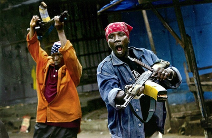 THREATENING STANCE: Fighters supporting President Charles Taylor course through Monrovia's central marketplace. (Carolyn Cole)