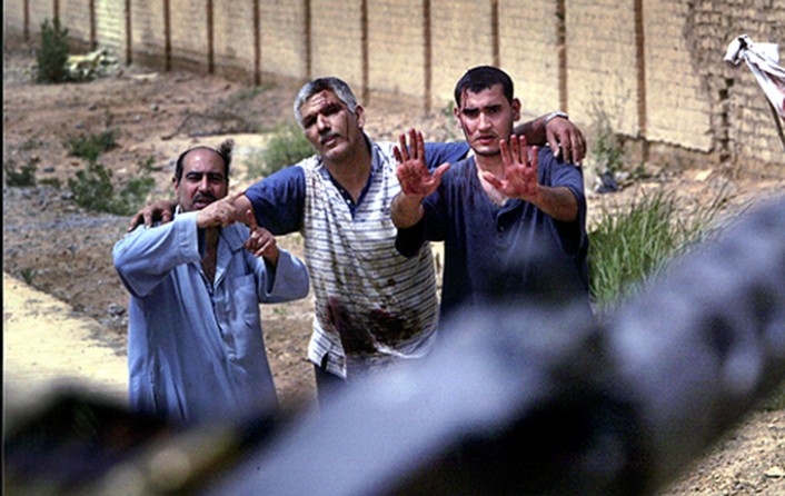 Wounded in an aerial bombing of Baghdad and seeking aid, Iraqi civilians raise their hands pleadingly toward advancing troops of the 3rd Infantry Division. (David Leeson)