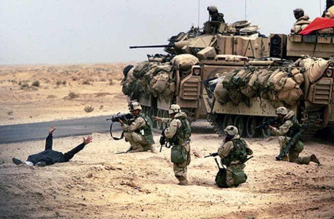 Arms outstretched in surrender after being stopped along a road en route to Baghdad, an armed suspect is surrounded by U.S. troops from the 3rd Infantry Division. On the fourth day of war, Iraq already was feeling U.S. might. (David Leeson)