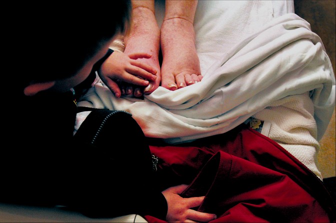 During a hospital visit, EJ touches Carolynne's swollen feet where Melissa had painted her toenails. Fluid build-up in her legs was one factor that forced Carolynne to stop chemotherapy. After a week in the hospital, she was sent home under hospice care. (1/13/07)