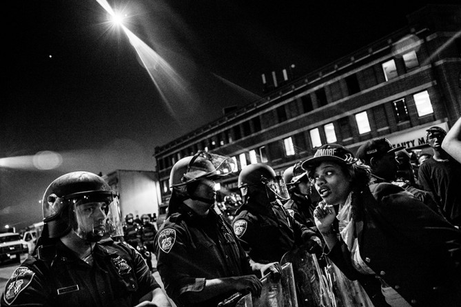 A helicopter with a spot light watches over police and protesters before a mandatory, city-wide curfew of 10 p.m. near the CVS pharmacy that was set on fire yesterday during rioting after the funeral of Freddie Gray in Baltimore, Maryland. Gray, 25, was arrested for possessing a switch blade knife April 12 outside the Gilmor Houses housing project on Baltimore's west side. According to his attorney, Gray died a week later in the hospital from a severe spinal cord injury he received while in police custody (