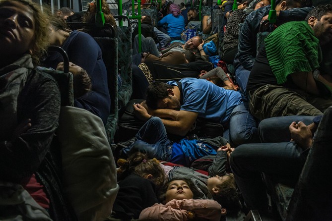 Ahmad Majid, in blue T-shirt at center, sleeps on a bus floor with his children, his brother Farid Majid, in green sweater at right, and other members of their family and dozens of other refugees, after leaving Budapest on the way to Vienna. Hundreds of thousands of refugees, mostly from Afghanistan, Iraq and Syria, fled their homes, risking their lives in dangerous boat trips, illegal border crossings and long bus and train journeys, seeking asylum in Western Europe and Scandinavia (Mauricio Lima, The New 