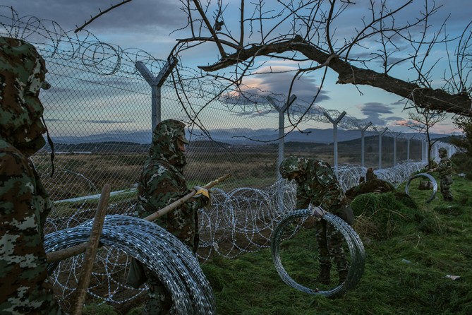 Macedonian soldiers on the Greek side of the border have built a border fence that divides their town of Gevgelija, in the background, from Idomeni, in Greece, where nearly 2,500 refugees were being barred from entering (Mauricio Lima, The New York Times - November 28, 2015).
