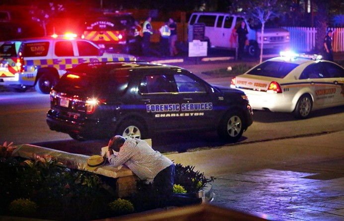 Multiple law enforcement agencies canvas the grounds of Emanuel AME Church in Charleston as the Rev. Anthony Thompson collapses in grief along Calhoun Street while waiting for news about his wife, Myra Thompson, after a mass shooting during a Bible study. Thompson's wife was among nine people killed in the shooting (Wade Spees, The Post and Courier - July 17, 2015).