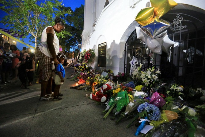 Phyllis Holmes of Charleston takes a moment to pray with her 3-year-old granddaughter after placing a candle at a memorial on the sidewalk in front of Emanuel AME Church in Charleston. The stunned city tried to come to grips with tragedy a day after a mass shooting at the church left nine people dead (Paul Zoeller, The Post and Courier - July 18, 2015).