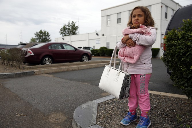 Mimi waits outside the clinic in Chelsea holding her mom's purse and their new puppy, while Raquel gets her dose of methadone. Raquel gave in to Mimi's begging to bring the puppy to the clinic, not realizing that animals weren't allowed inside (Jessica Rinaldi, The Boston Globe).