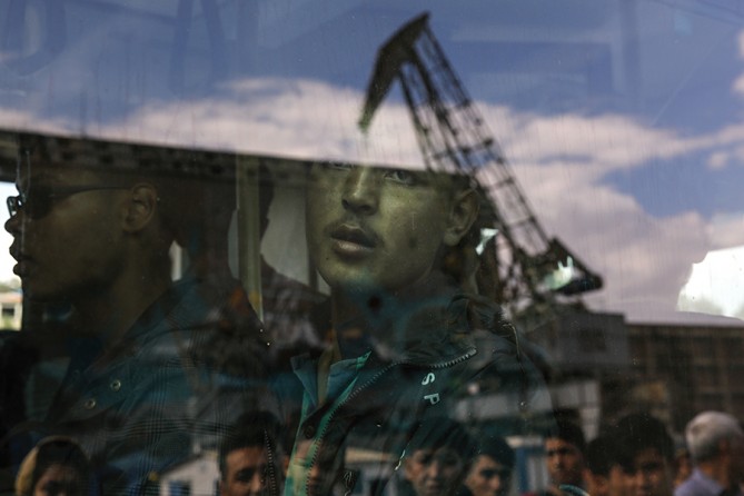 An Afghan migrant is seen inside a bus following his arrival by the Eleftherios Venizelos passenger ferry with over 2,500 migrants and refugees from the island of Lesbos at the port of Piraeus, near Athens, Greece (Yannis Behrakis, Thomson Reuters - October 8, 2015).