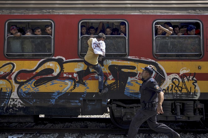 A policeman tries to stop a migrant from boarding a train through a window at Gevgelija train station in Macedonia, close to the border with Greece (Stoyan Nenov, Thomson Reuters - August 15, 2015). 