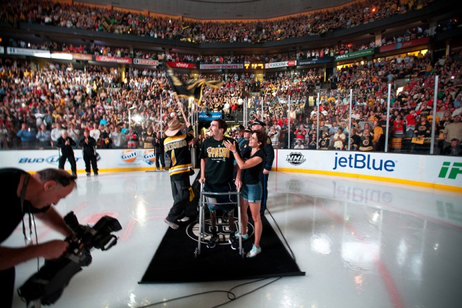 Invited by the Boston Bruins to appear before Game 6 of the Stanley Cup finals, Bauman stood and took a few steps, accompanied by his outpatient physical therapist, Michelle Kerr. At left, in the cowboy hat, is Carlos Arredondo, a bystander who helped Bauman shortly after the bombs detonated. Jeff did not want to appear, but his mother encouraged him and eventually convinced him, saying, 'this country needs some hope right now.' (Josh Haner, The New York Times - June 24, 2013)