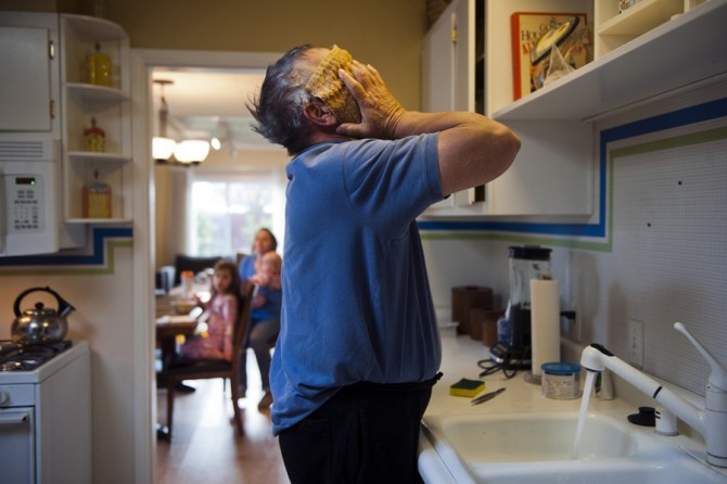 Always within eyesight of his grandchildren, Don Hatfield washes his face and hair in the kitchen sink so he can attend to Alex, 10 months, Ariel, 3, and Eva, 4, as the babysitter arrives.  (April 6, 2012)
