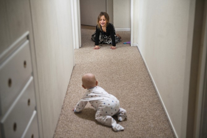 Eva, 4, cheers her brother Alex, 10 months, as he learns how to crawl in the hallway of their new home in Napa. (April 6, 2012)
