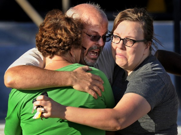 Tom Sullivan, center, hugs his wife Terry, left, and daughter Megan outside Gateway High School, Friday July 20, 2012, in Aurora. (RJ Sangosti - July 21, 2012)