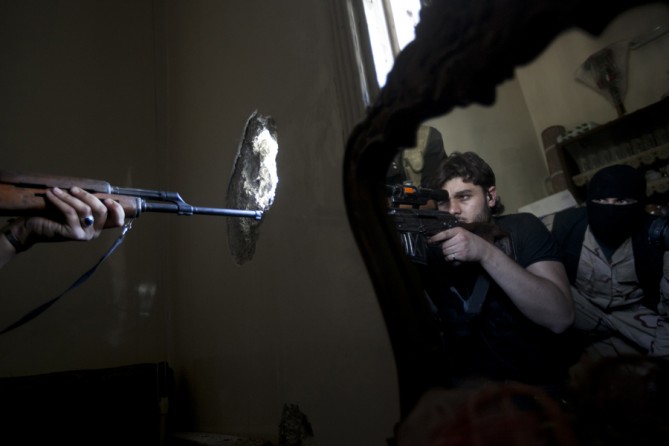 A rebel sniper aims at a Syrian army position, as he and another rebel fighter are reflected in a mirror inside a residential building in the Jedida district of Aleppo, Syria, Oct. 29, 2012. (Narciso Contreras, Associated Press - October 29, 2012)