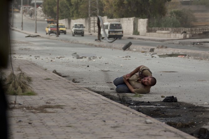 A wounded Syrian civilian lies in the street with a shot to his stomach as he tries to escape the line of fire after he was targeted by a Syrian army sniper while walking near the frontline in the Bustan al-Qasr neighborhood of Aleppo, Syria, Oct. 20, 2012. (Narciso Contreras, Associated Press - October 20, 2012)