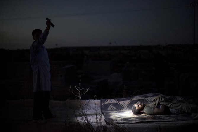A man points a flashlight towards the body of a Syrian man killed by Syrian army shelling at a graveyard, in Aleppo, Syria, Oct. 13, 2012.   (Manu Brabo, Associated Press - October 13, 2012)