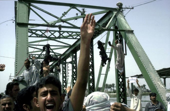 Fallujah - Iraqis chant anti-American slogans as the charred bodies of four U.S. contractors hang from a bridge over the Euphrates River. The incident marked increased violence by insurgents based in Fellujah. 