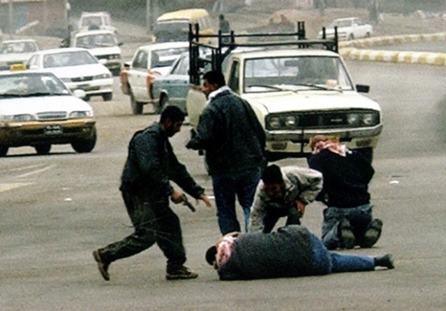 Baghdad - A gunman, left, shoots an Iraqi election worker during an attack on Haifa Street, a base of Sunni Arab insurgents. About 30 men attacked a car carrying five of the workers, executing three at point blank range. 