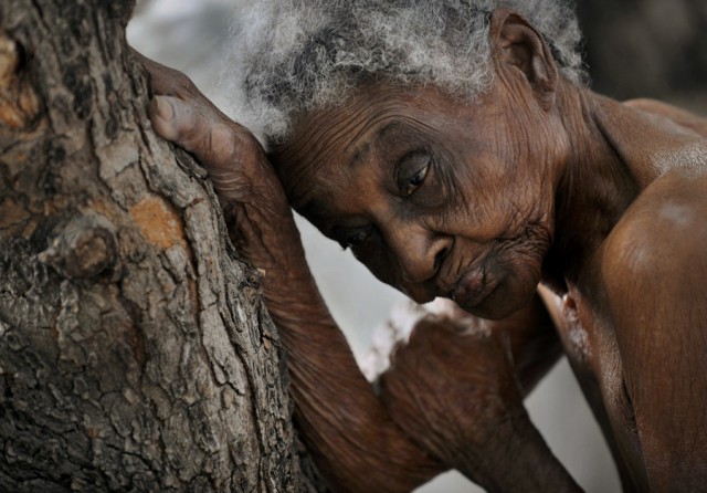 'The Elderly'  Idamise Pierre leans against a tree, her withered skin resembling its bark, as she waits to bathe at the Azil Communal Home for the Aging.  With weary resignation, the elderly have endured decades of Haiti's poverty and political turmoil and in their twilight years are now left with heavy hearts by the earthquake that eternally altered their lives. (Nikki Kahn, The Washington Post - March 13, 2010)