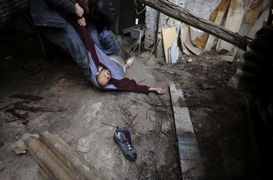 Syrian rebels lift a comrade who was shot by Army sniper fire after they prepared to attack a government held checkpoint in the Ain Tarma neighborhood of Damascus. (January 30, 2013)