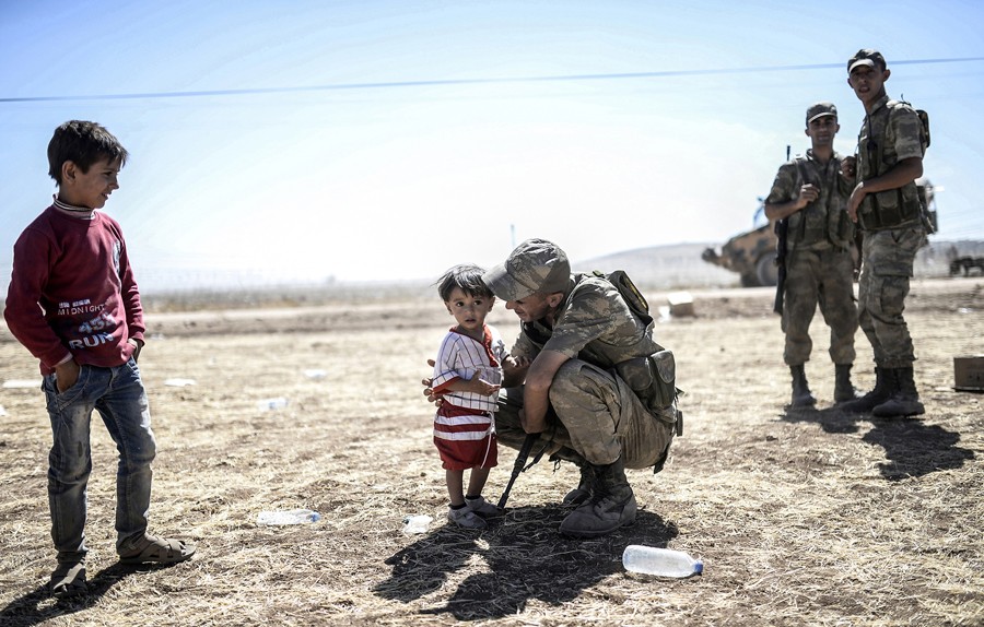 A Turkish soldier kisses Syrian Kurds children in Sanliurfa province, on September 20, 2014, after they crossed the border between Syria and Turkey near the southeastern town of Suruc. Several thousand Syrian Kurds began crossing into Turkey on September 19 fleeing Islamic State fighters who advanced into their villages. (Bülent Kılıç/AFP)