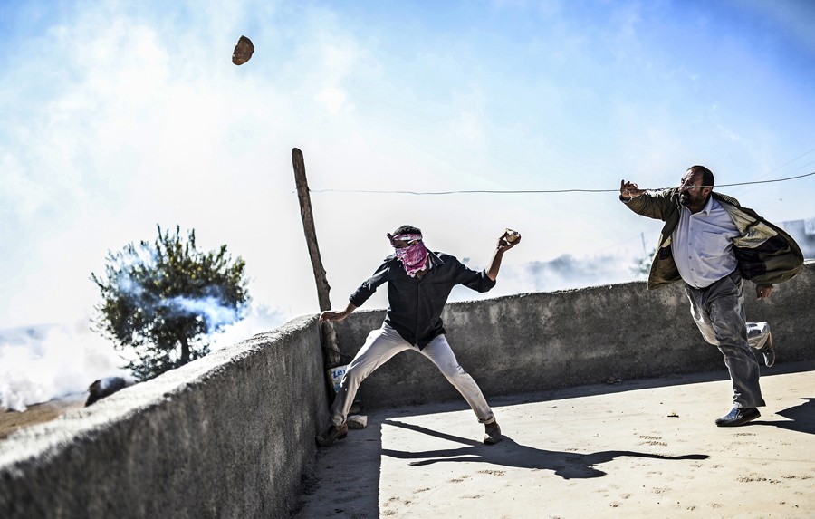 Kurdish protesters throw stones at Turkish soldiers during clashes near the Syrian border after Turkish authorities temporarily closed the border at the southeastern town of Suruc in Sanliurfa province, on September 21, 2014. (Bülent Kılıç/AFP)