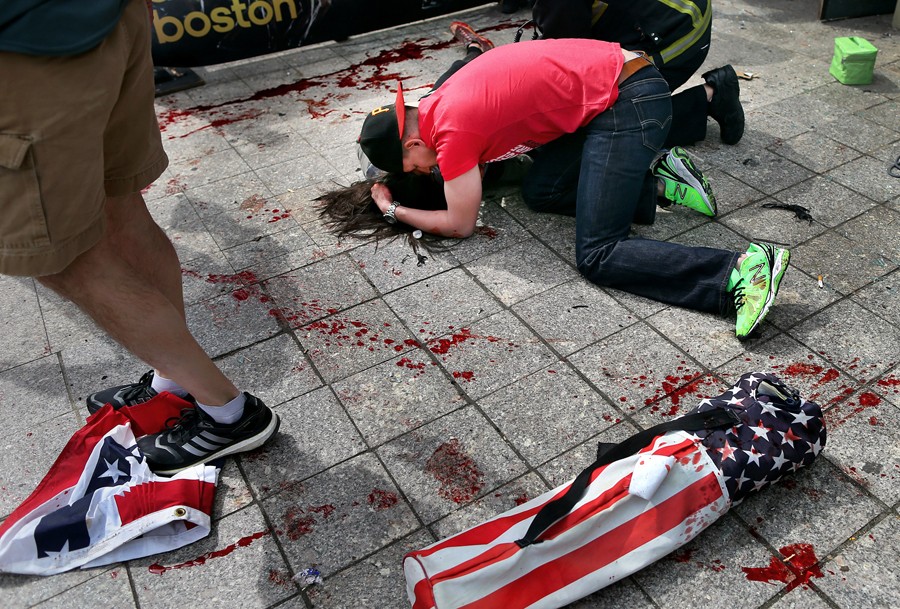 Joe Duncan comforts Sydney Corcoran at the site of the first bomb. She was standing with her parents Celeste and Kevin to cheer on her aunt, who was running in the race. She fell fifteen feet away from her mother, who lost both of her legs in the bombing. (Photo by John Tlumacki, April 16, 2013)