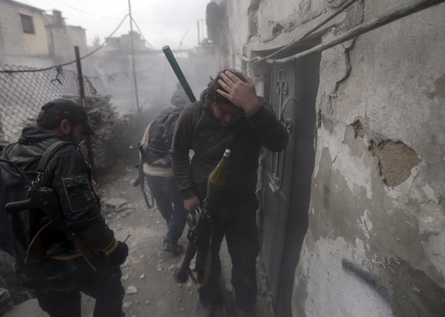 An injured Syrian rebel fighter holds his head soon after a tank shell, fired by the Syrian Army, exploded on a nearby wall during fighting in the Ain Tarma neighborhood of Damascus (January 30, 2013)