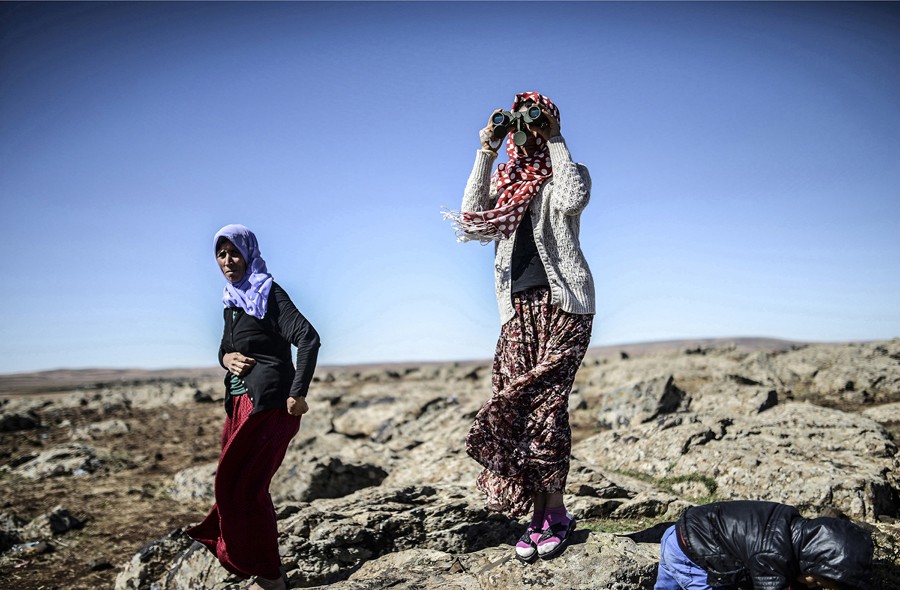 Members of the Syrian Kurdish Altay family try to spot on October 20, 2014 from the Turkish Syrian border village of Mursitpinar, their relative, Zamani Suruc, who is fighting Islamic State (IS) jihadists in the Syrian border town of Kobane. (Bülent Kılıç/AFP)