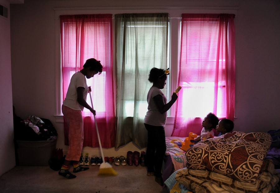 Washington, D.C.: Dasha, 14, left, cleans while her sister Dashanna, 12, entertains 2-year-old twins Jada and Jaden with a rattle. The twins, the children of Raphael Richmond's sister, often stay at the house when their mother is at work, further straining the food supply. The family goes to food banks and other charities more often as food runs out earlier in the month. (December 16, 2013)