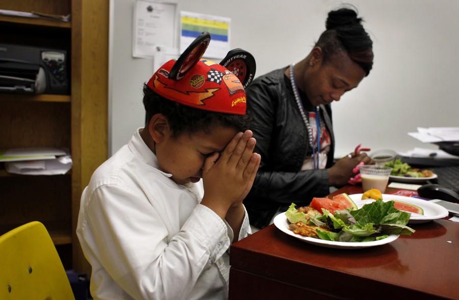 Solomon Jonthan and Crystal Watson-Johnson bow their heads to pray before eating their lunch at her desk in the restoration room. Solomon was sent to the restoration room for disrupting class after a fellow student made him believe he wouldn't get to eat lunch. To make him feel better, Crystal Watson-Johnson ate with him. (August 25, 2013)