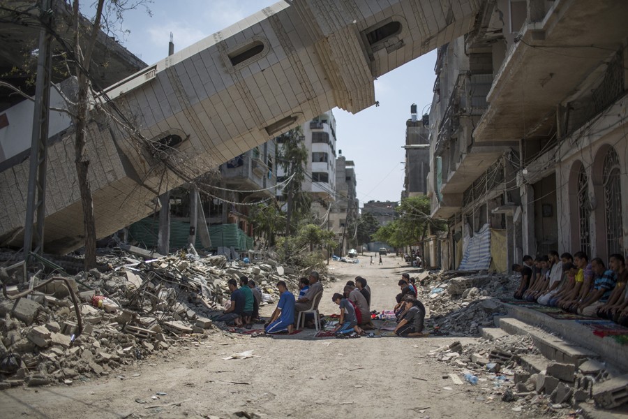 Aug. 15, 2014. Palestinian men pray beneath a toppled minaret at a mosque in Gaza. (Wissam Nassar for The New York Times)