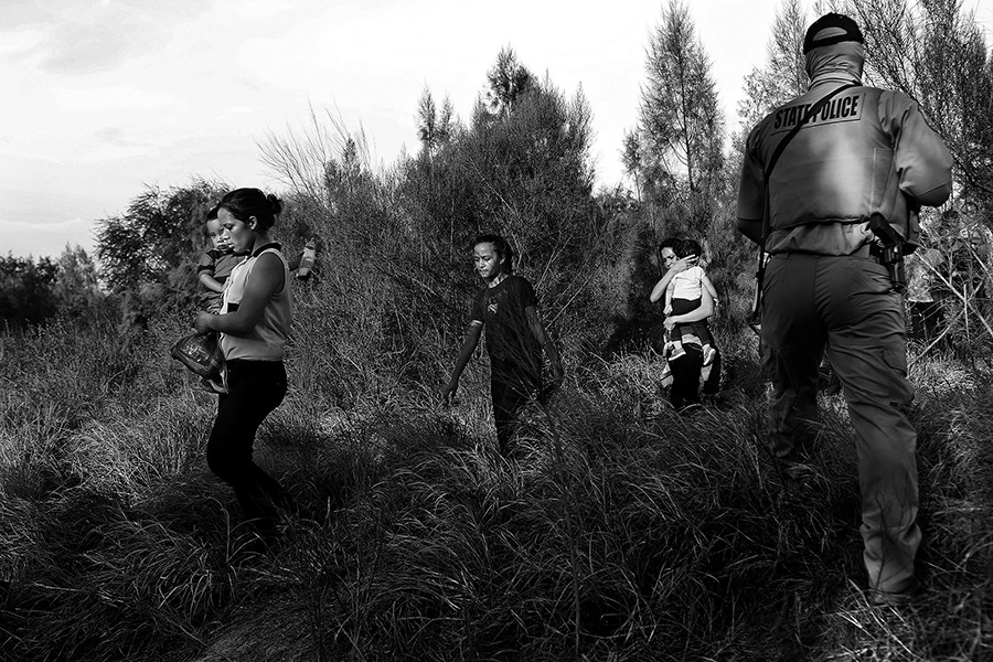 Central American immigrants including Maria Bertalina Ramirez, 21, left, of Honduras, with her son, Jose Joel, 1, are guided by Texas Game Wardens and a U.S. Border Patrol agent after they crossed the Rio Grande River by boat into the United States on Wednesday, August 13, 2014. The group of 14 was questioned and taken in vans to be processed. (Lisa Krantz/San Antonio Express-News)