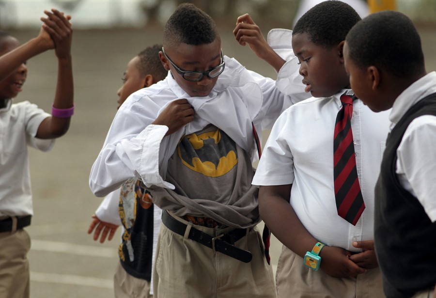 Ray Byrd, center, shows off his Batman t-shirt to Ciaran Johnson (l-r) and Alonzo Swift as they prepare to go back to their fourth-grade class after recess. The boys were putting their clothes back in place after playing hard during their break. (August 25, 2013)