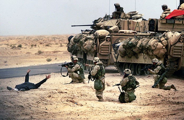 Arms outstretched in surrender after being stopped along a road en route to Baghdad, an armed suspect is surrounded by U.S. troops from the 3rd Infantry Division. On the fourth day of war, Iraq already was feeling U.S. might. (David Leeson)