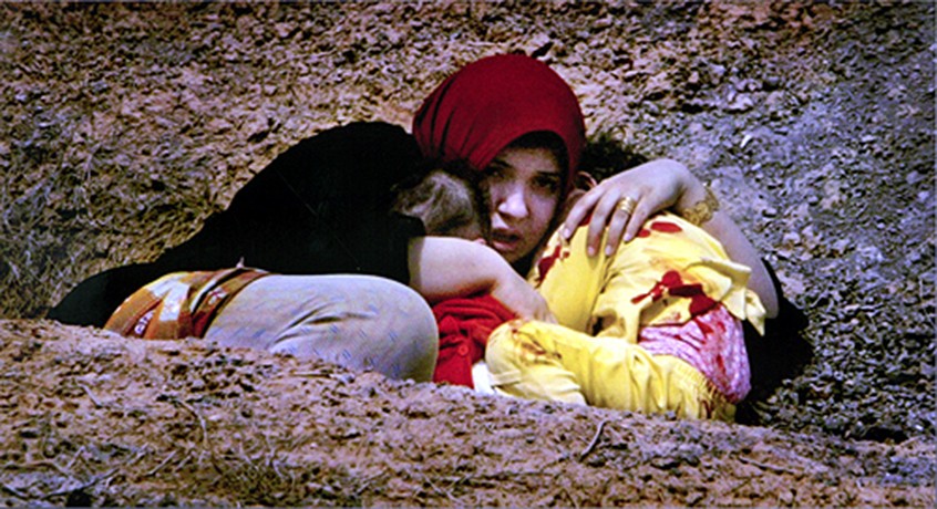 Caught in crossfire from the 3rd Intantry Division fighting through Northern Baghdad, a woman huddles in an open ditch with two terrified and bloodstained children. (David Leeson)