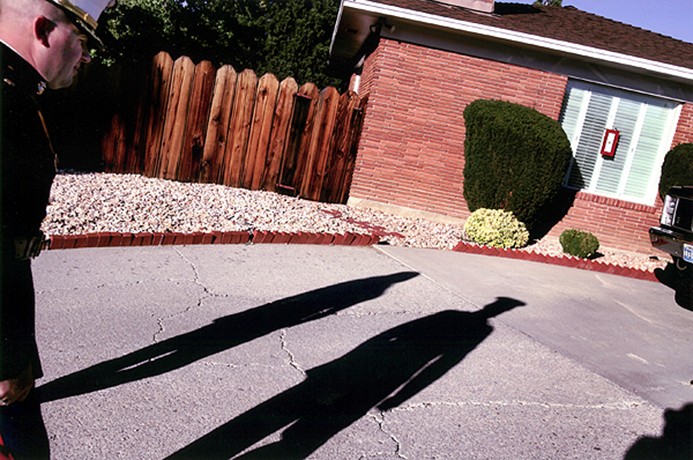 Major Steve Beck and another Marine approach the family home of 2nd Lt. James Cathey, preparing to escort the Catheys to the airport to receive their son's body. Five days earlier, the shadows of Casualty Assistance Call Officers followed the same path, carrying the news no military family ever wants to hear. "I'll never forget Major Beck's profile." Said Bob Burns of the night he was notified of his son's death. The gold star flag in the window signifies the death of a loved one oversees.