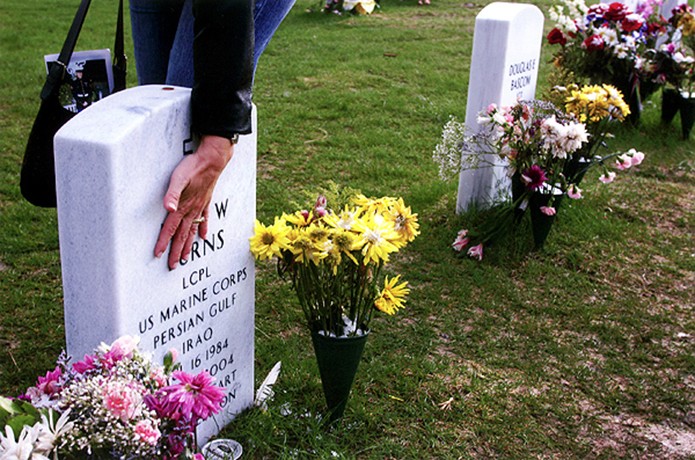 While visiting Denver for a ceremony honoring fallen Marines, Lori DeMille, Oceanside, Calif., touches the headstone of Marine Lance Corporal Kyle Burns, who was killed in Fallujah on November 11, 2004, at Fort Logan National Cemetery. DeMille and a group of Marines who served with Burns in Iraq came to Colorado to pay their respects to Burns and his family.